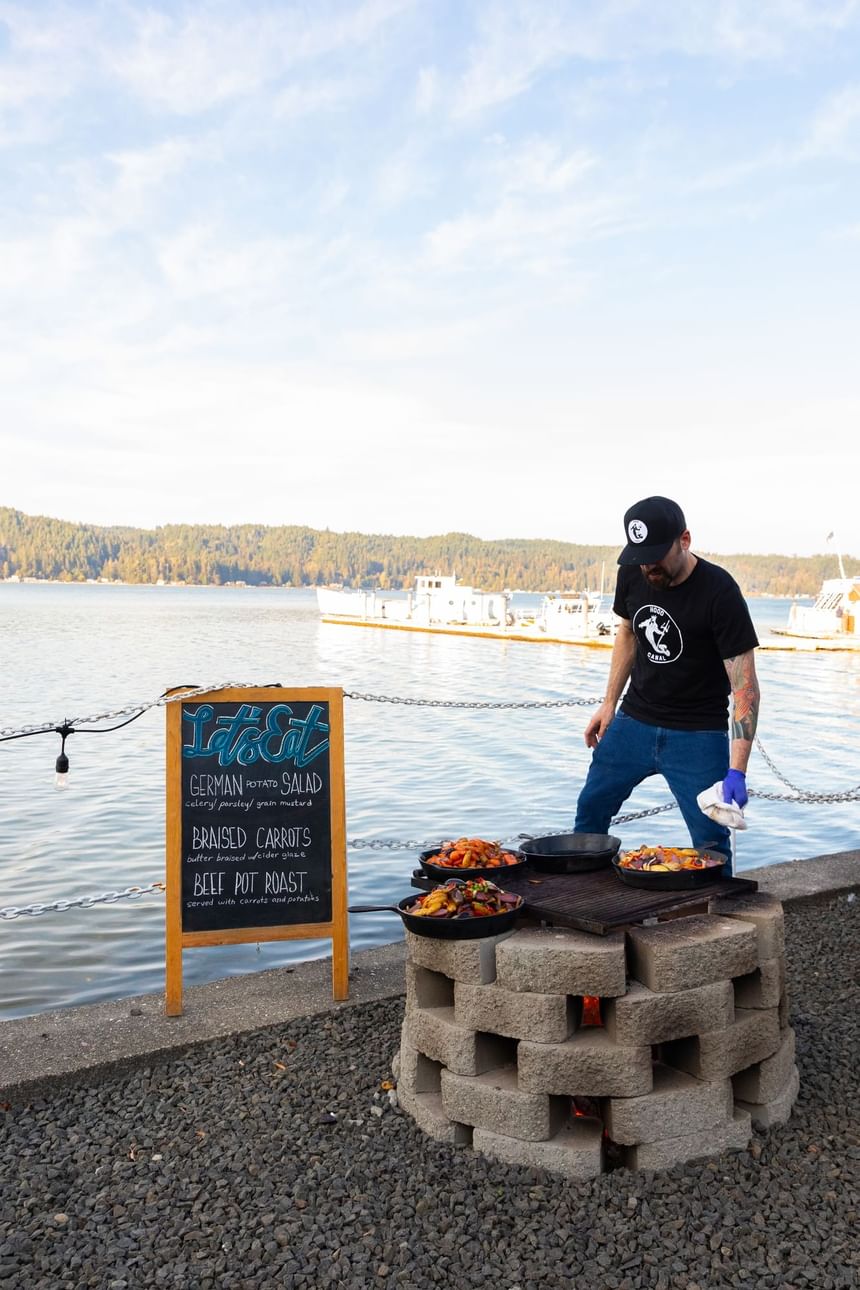 Man grilling food outdoors on a barbecue in Hook & Fork near Alderbrook Resort & Spa