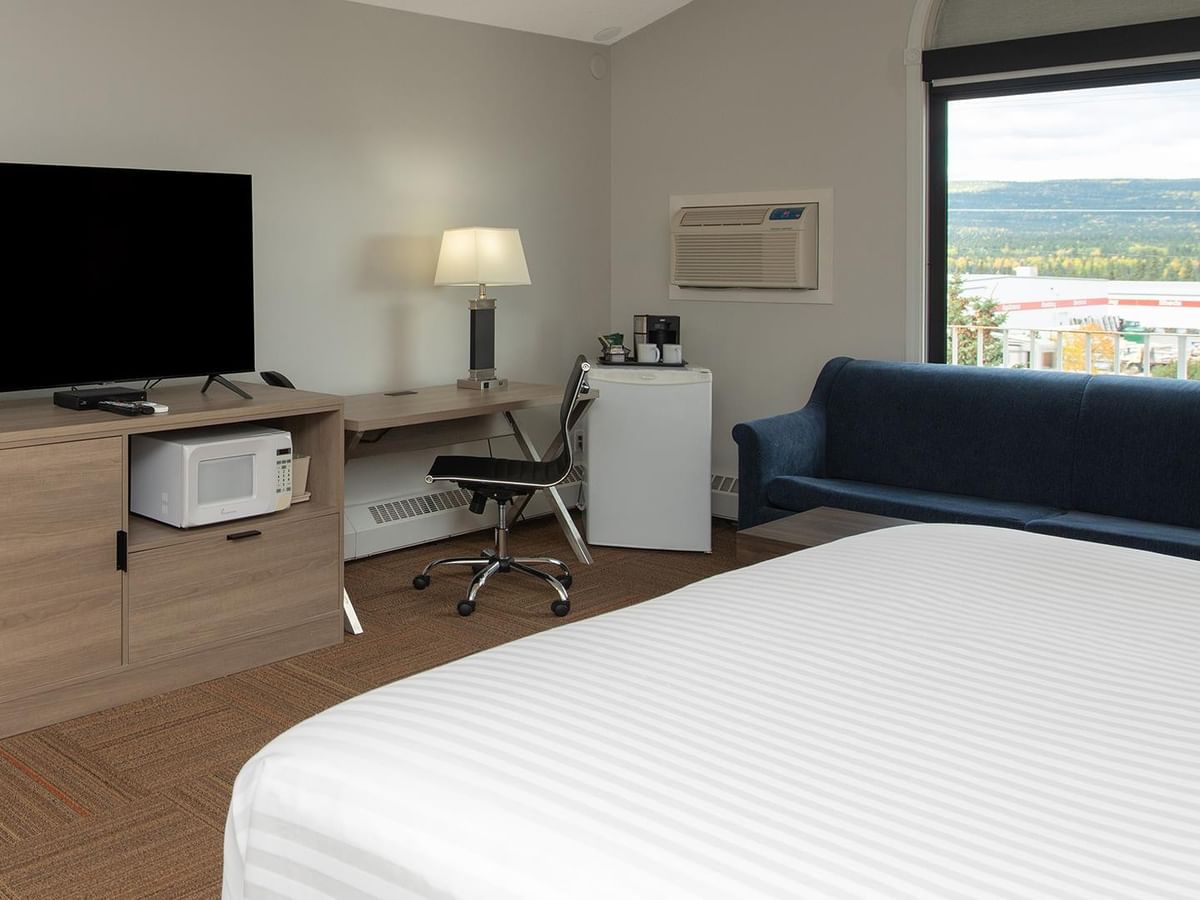 Coast Premium King Suite with Soaker Tub featuring king bed, blue sofa, and mountain views.