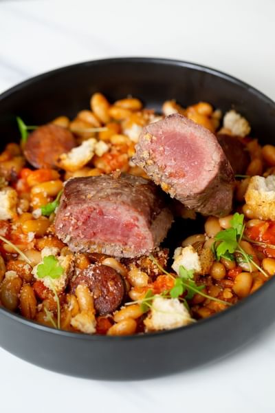 Close-up of meat and beans served in black bowl at Stein Eriksen Residences