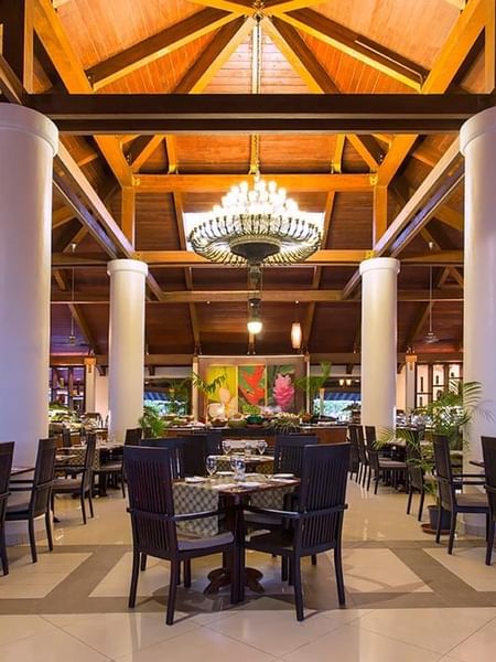 High wooden ceilings and white pillars with tables in Lagoon Terrace Restaurant at Warwick Le Lagon 
