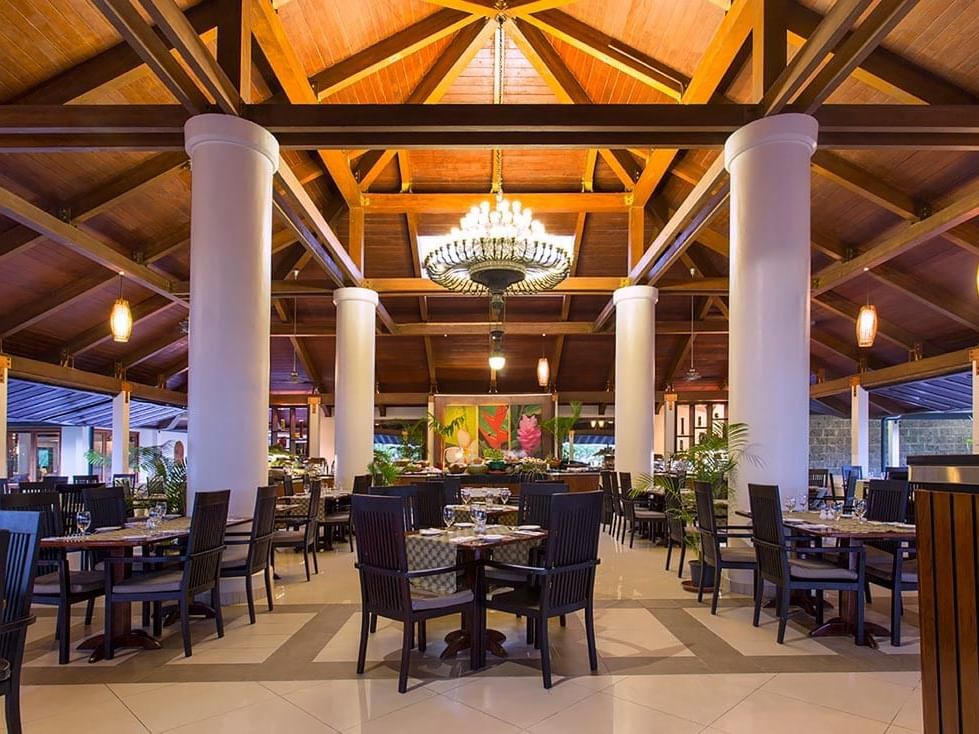 High wooden ceilings and white pillars with tables in Lagoon Terrace Restaurant at Warwick Le Lagon 