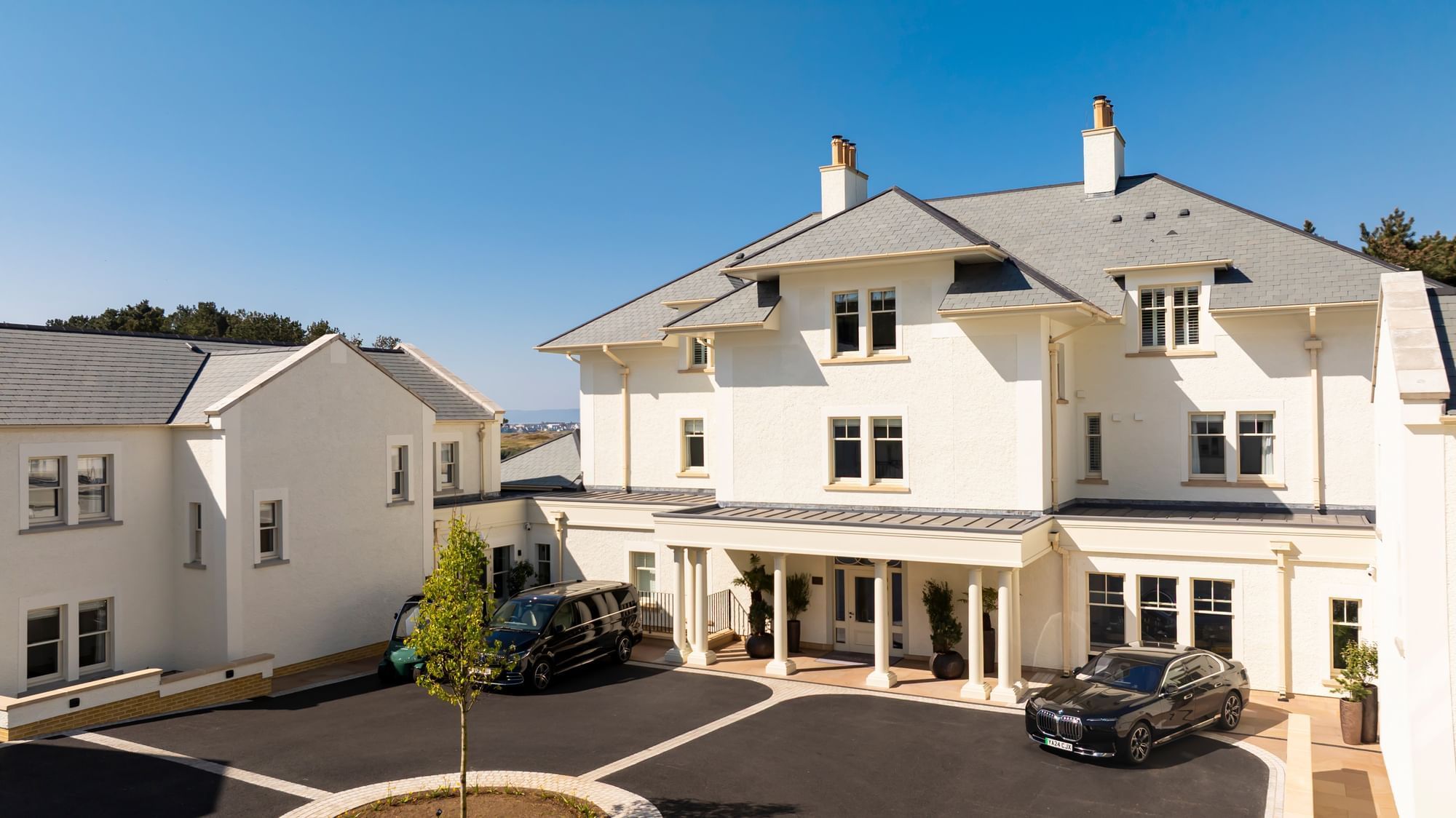 A sunny view of the white exterior of the main Dunluce Lodge building and the front driveway