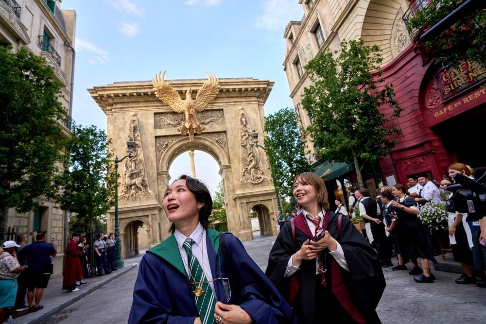 Two girls in Hogwarts robes wander through the wizarding streets of Paris in the wizarding world at Epic Universe.