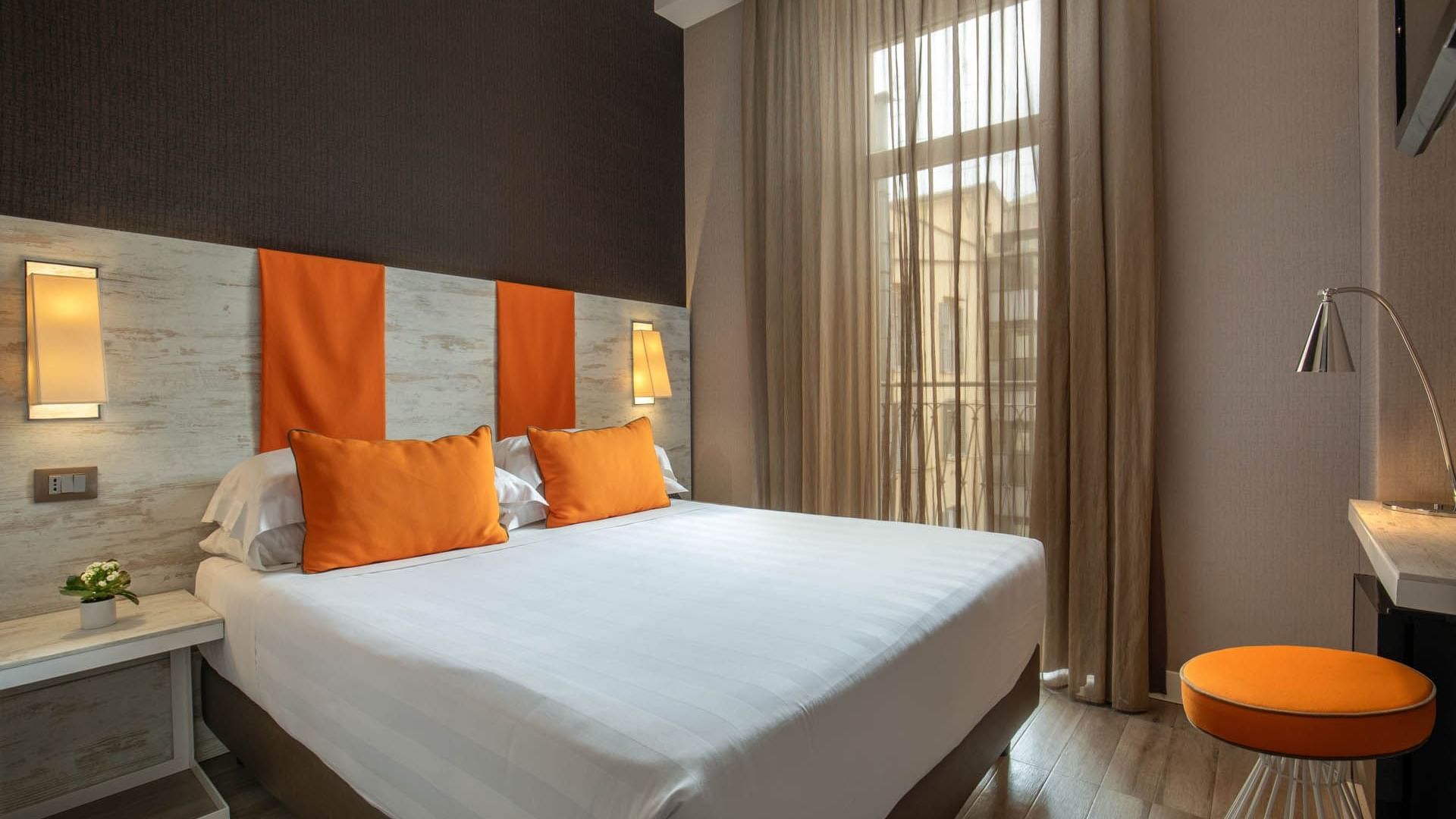 Bright Smart Room at The Guardian Hotel featuring a double bed, orange accents, a large window, and minimalist decor