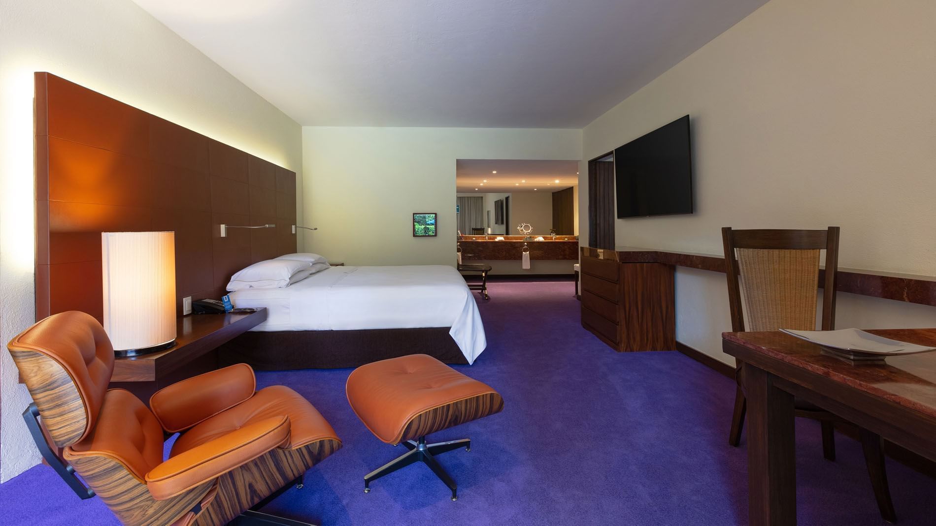 King Master Suite at Camino Real Polanco Mexico, featuring a leather headboard, purple floor, and an open bathroom