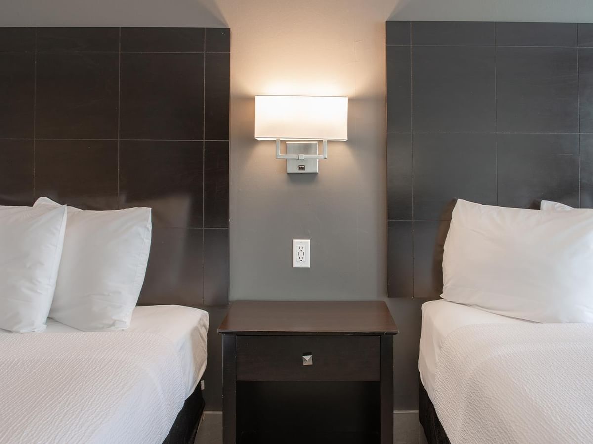 Two beds with white linens and pillows in a hotel room.