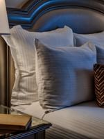 Glass lamp by a book on a nightstand under a padded headboard in Classic King Accessible at Warwick Melrose Dallas