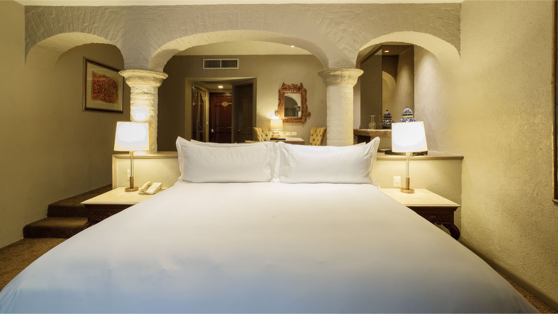 King Governor Suite featuring white bedding and stone architectural arches at Quinta Real Guadalajara