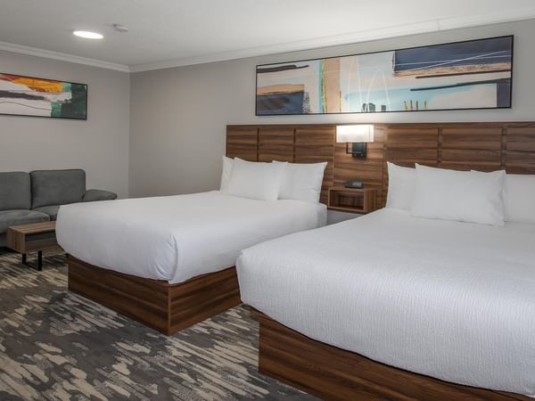 Spacious room with two queen beds and gray couch at Coast Dawson Creek Hotel.