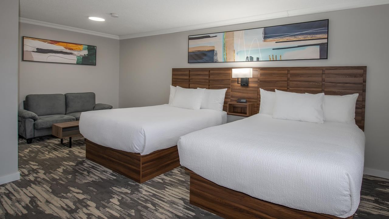 Spacious room with two queen beds and gray couch at Coast Dawson Creek Hotel.