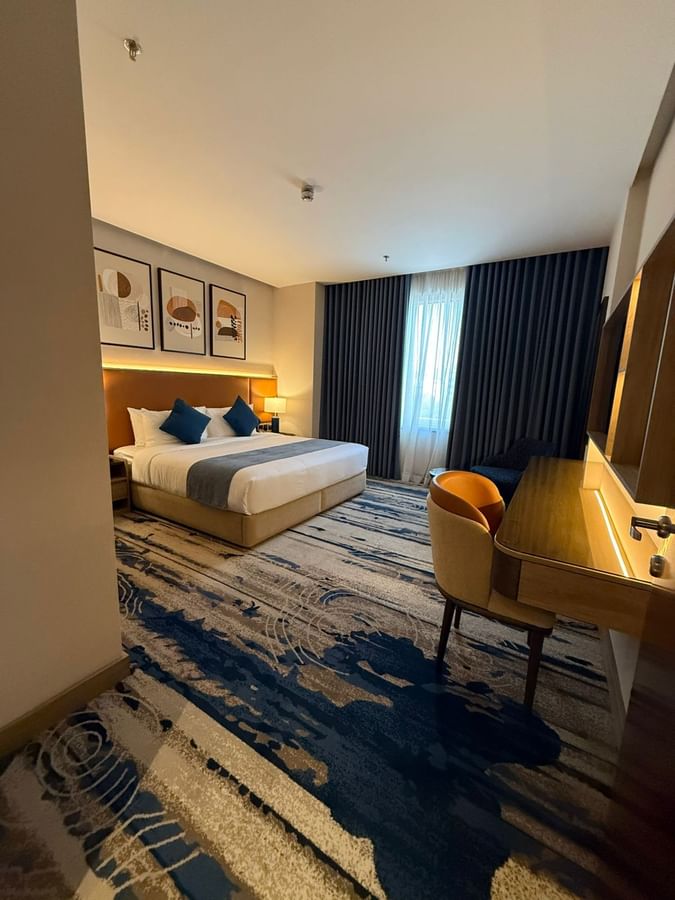 Work desk beside the bed and window-side couch in Deluxe Room at Warwick Jeddah Hotel & Spa