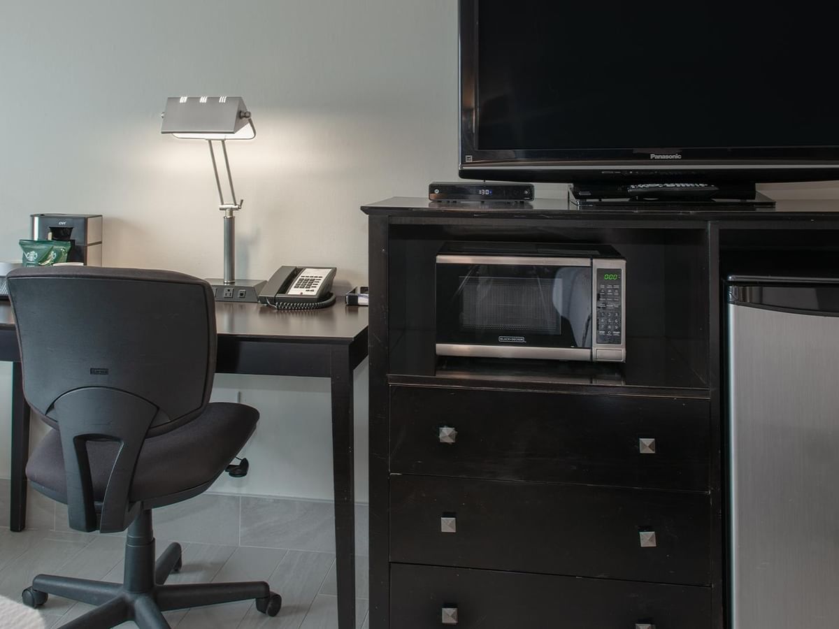 Office chair by desk with lamp and TV on dresser.