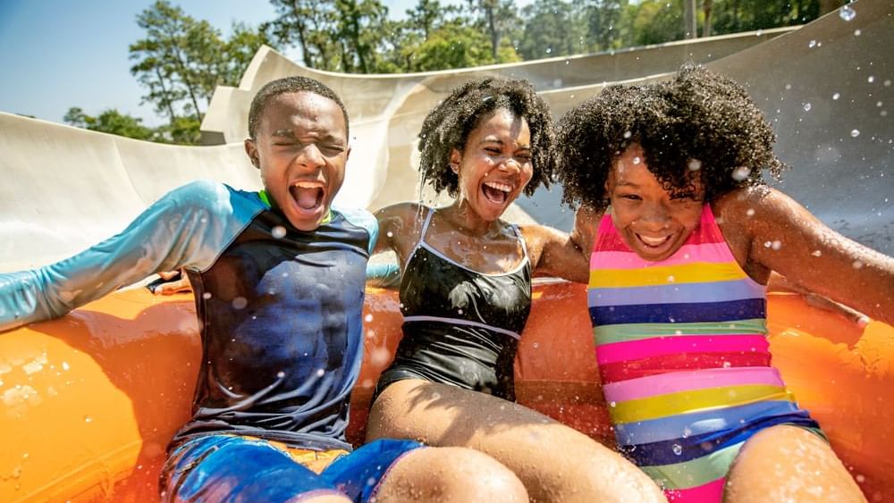 Three friends on waterslide at Walt Disney's Typhoon Lagoon Waterpark near Lake Buena Vista Resort Village & Spa