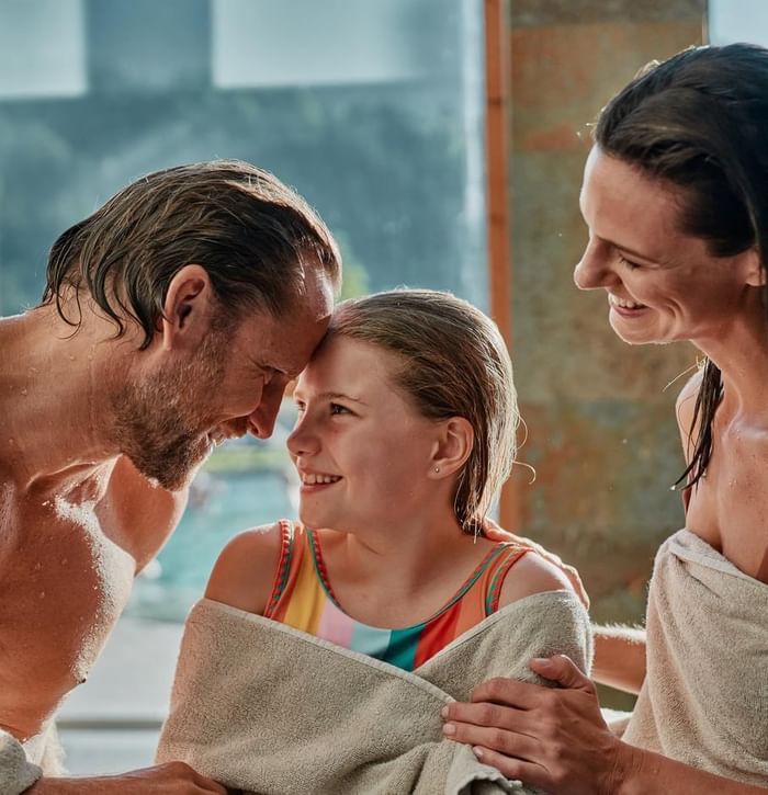 Vater, Mutter und Tochter trocknen sich nach dem Schwimmen im Wellnessbereich ab.