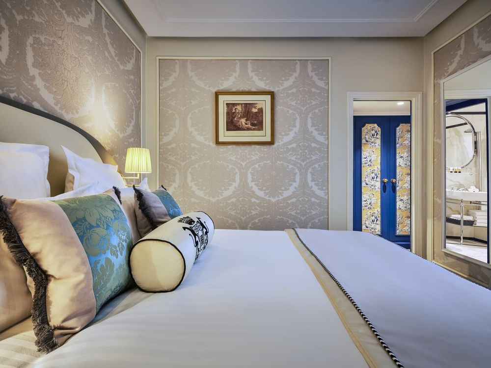 Élégante chambre Deluxe avec un grand lit, du papier peint à motifs et une vue sur Paris à l'Hôtel Westminster - Paris.