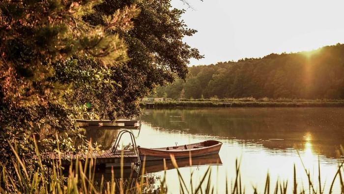 Lake Blaguš at sunset featuring wooden boat by the dock near Falkensteiner Premium Camping Lake Blaguš