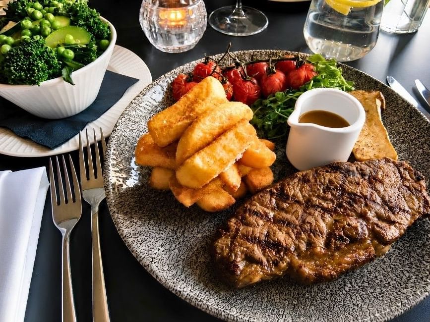 Grilled steak with chips, roasted tomatoes, and fresh greens served at The Terrace Restaurant, Easthampstead Park Hotel