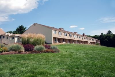 The Fox Ridge Resort building with several balconies and lawn chairs on a hill with green grass and colorful plants.