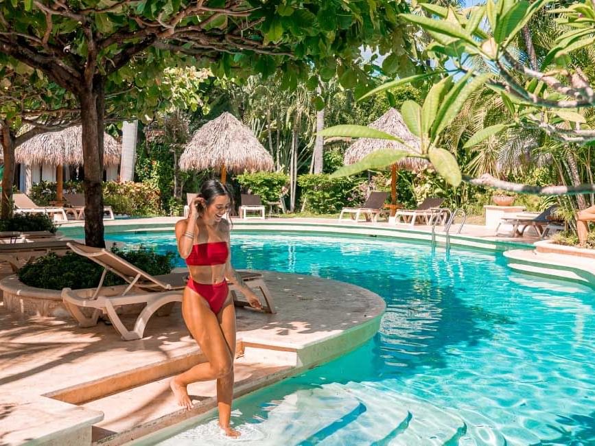 Una dama metiéndose a la piscina en Jardín del Edén Boutique Hotel