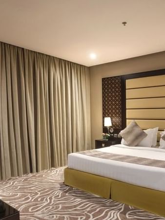 Standard King / Twin Bed features King-sized bed by a dark wood nightstand at Naviti by Warwick Al Khobar