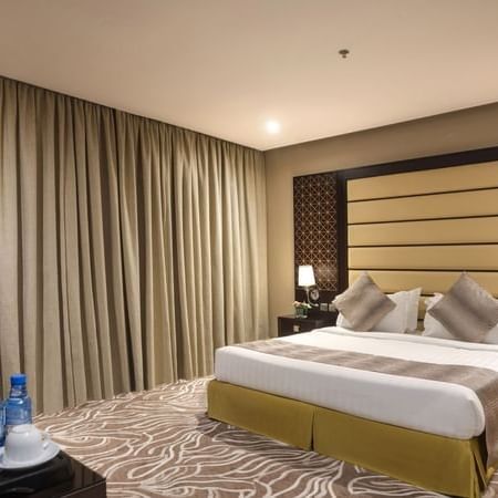 Standard King / Twin Bed features King-sized bed by a dark wood nightstand at Naviti by Warwick Al Khobar