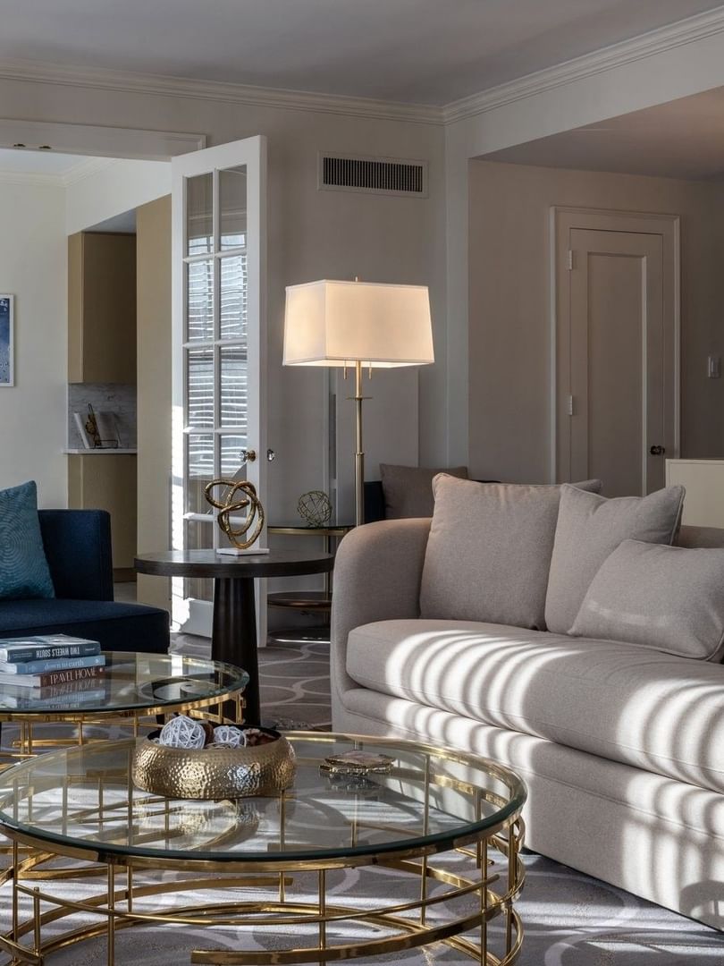 Presidential Suite features a Tan sofa with gold glass tables under a white floor lamp at Warwick Melrose Dallas