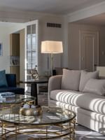 Presidential Suite features a Tan sofa with gold glass tables under a white floor lamp at Warwick Melrose Dallas