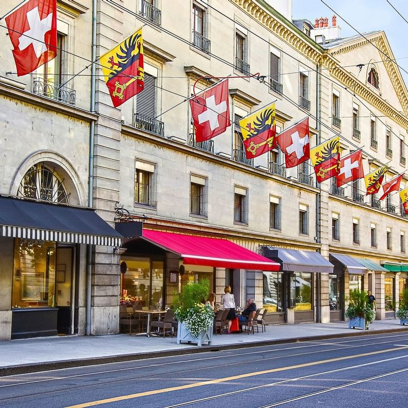 Geneva street view featuring cafes, colorful flags fluttering above a historic building near Warwick Hotels and Resorts