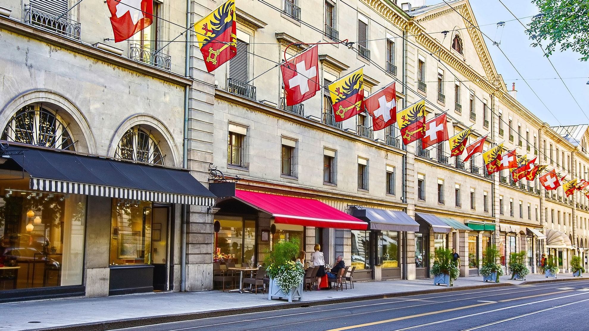 Geneva street view featuring cafes, colorful flags fluttering above a historic building near Warwick Hotels and Resorts