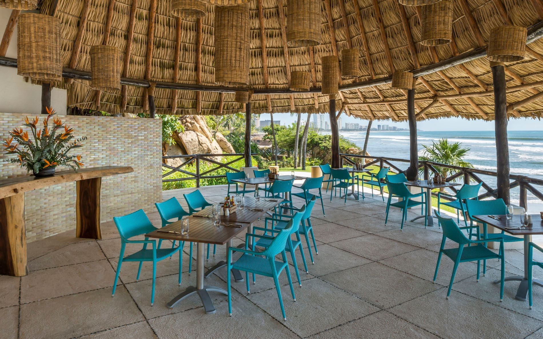 La Bocana restaurant featuring turquoise chairs and wicker lamps with views of the coastline at Quinta Real Acapulco