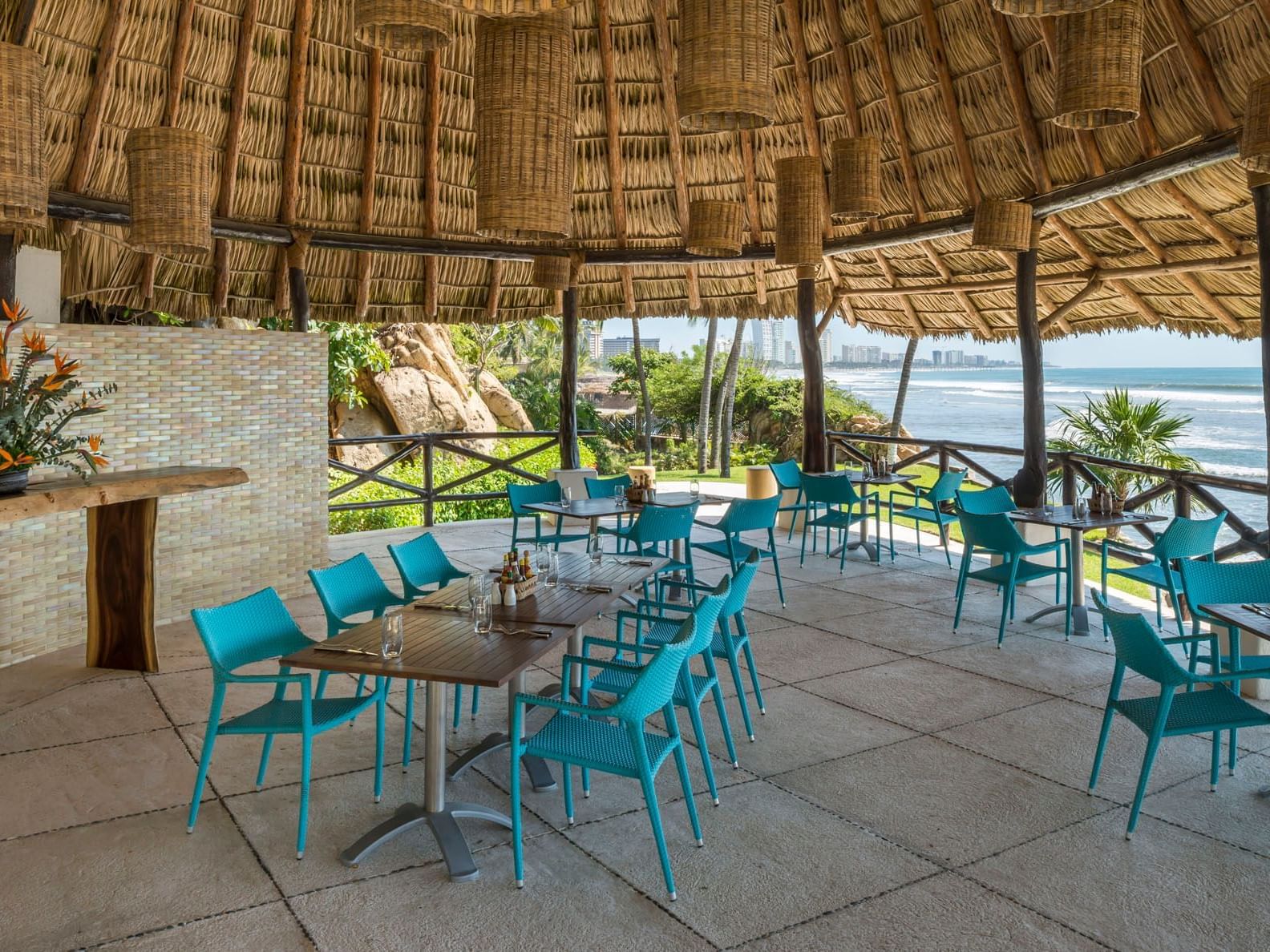 La Bocana restaurant featuring turquoise chairs and wicker lamps with views of the coastline at Quinta Real Acapulco