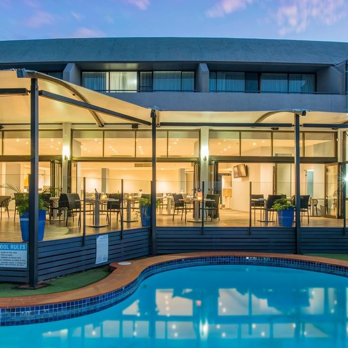 Outdoor pool area beside the dining area with a warm lighting in the evening at Mercure Charlestown