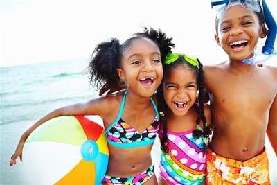 Kids posing for a picture with a beach ball and sea backdrop at Accra Beach Hotel & Spa