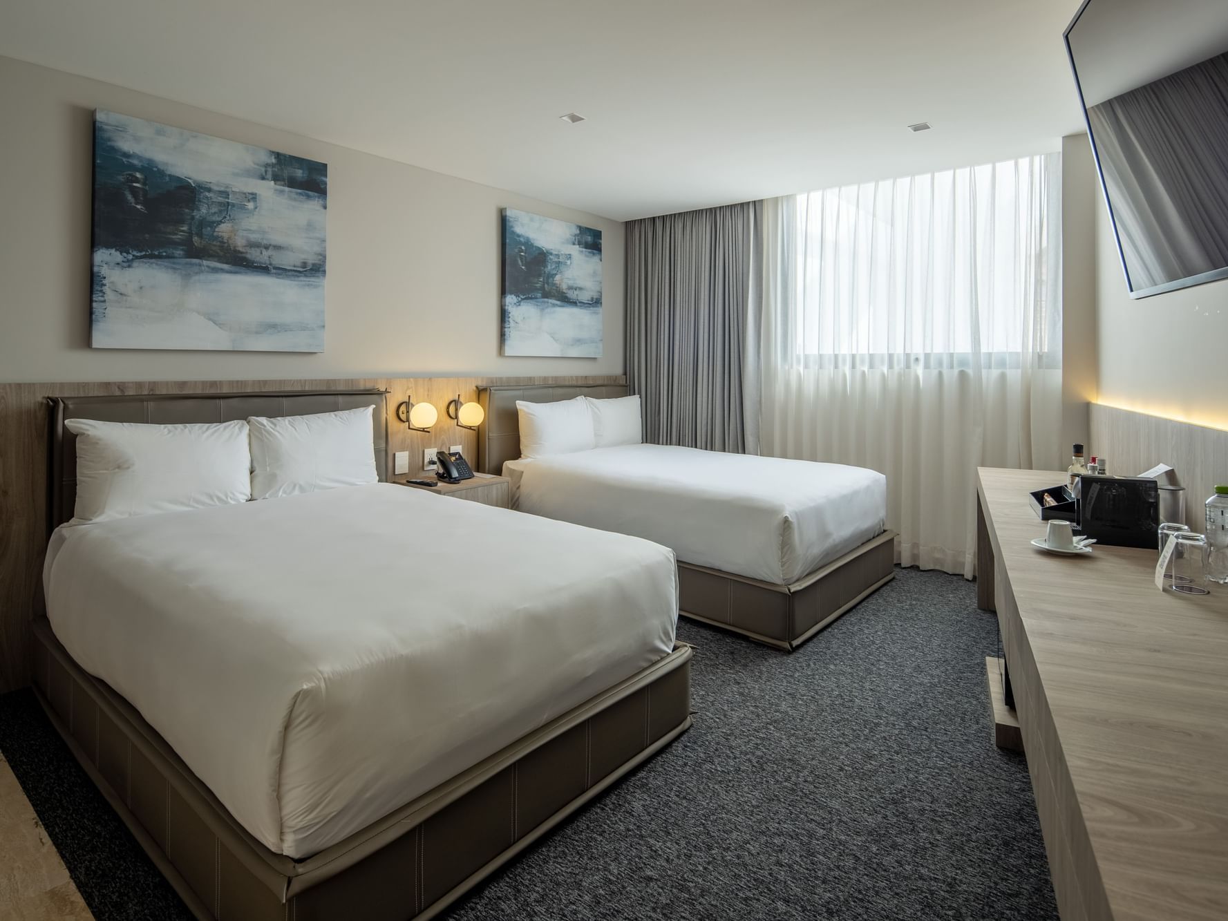 Two deluxe double beds with white linens and modern decor at Elements by Marquis in Ciudad de México.