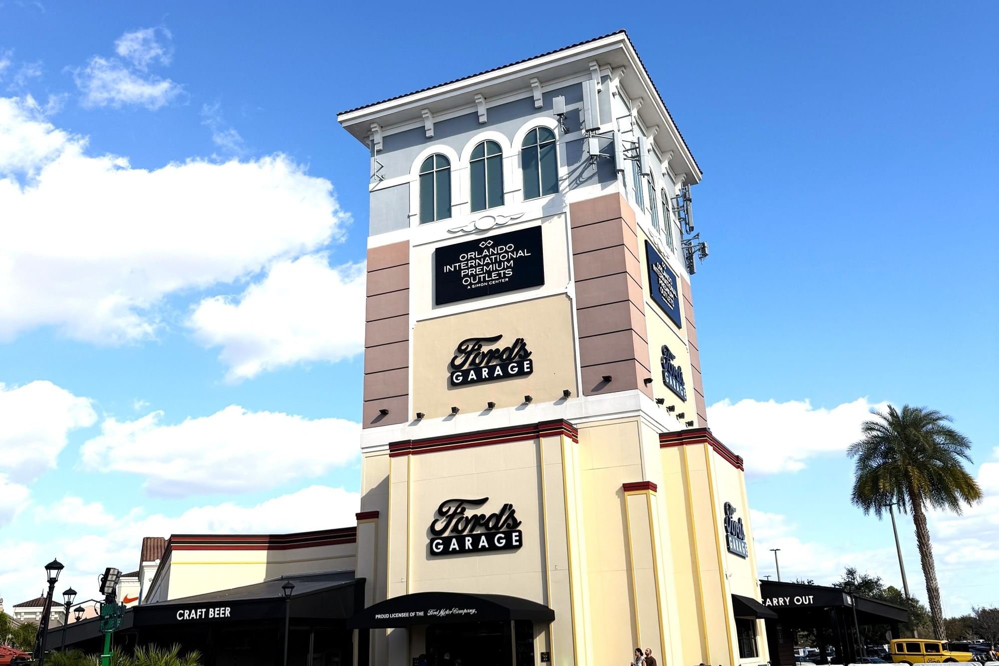 A tower with windows and signs for Ford's Garage and the Orlando International Premium Outlets. 