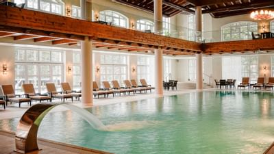 Indoor pool area with deck chairs at Ana Hotels Sport