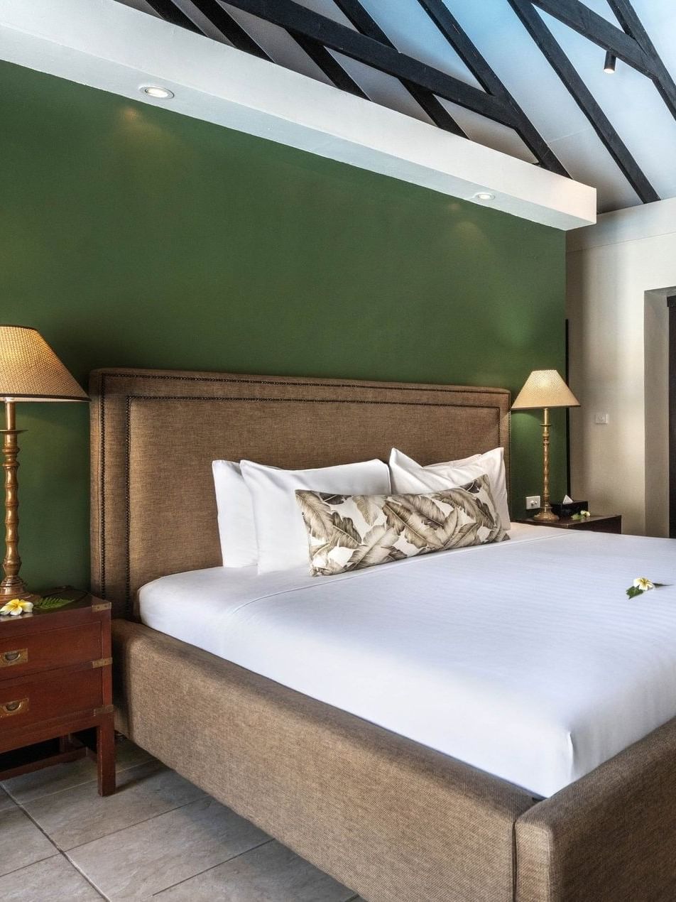 White bed facing dark wood desk & chair and dark wood sliding doors in Pacific Pool Villa at warwick le lagon-vanuatu 