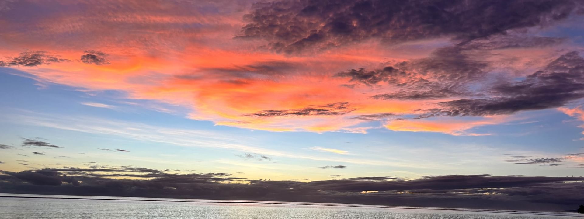 Calm sea under a vibrant pink and purple sunset sky with scattered clouds near Warwick Fiji Resort and Spa Korolevu