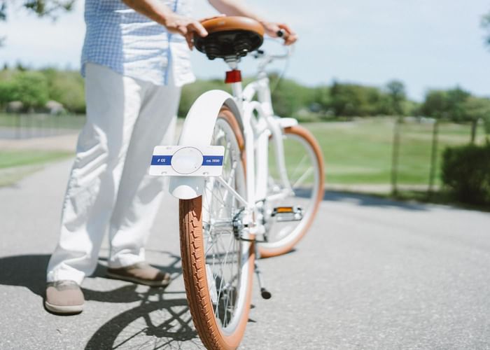A person standing with a white bicycle with brown tires at Ogunquit Collection