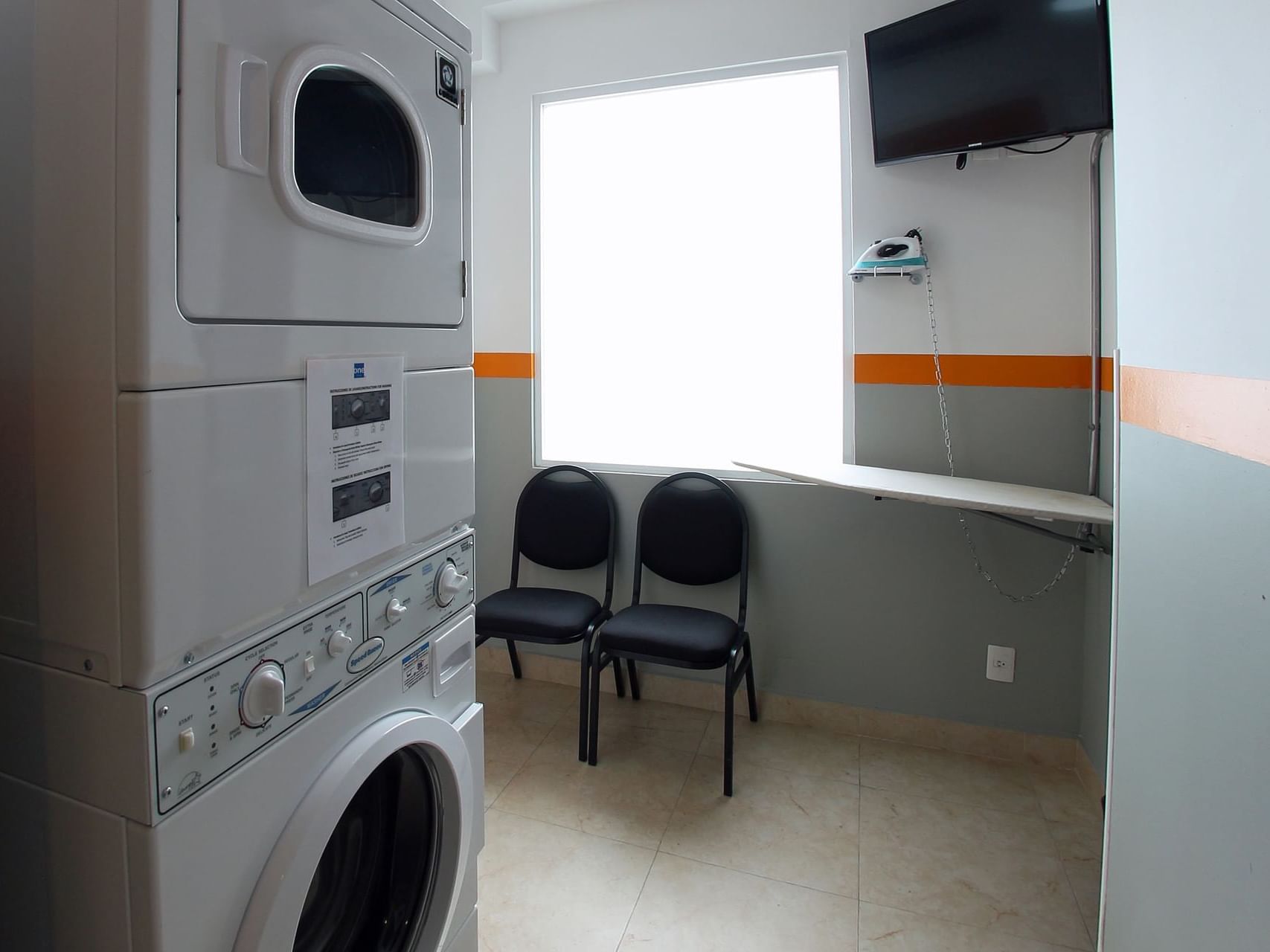 Lavadora, secadora y sillas en la sala de lavandería de One Hotels