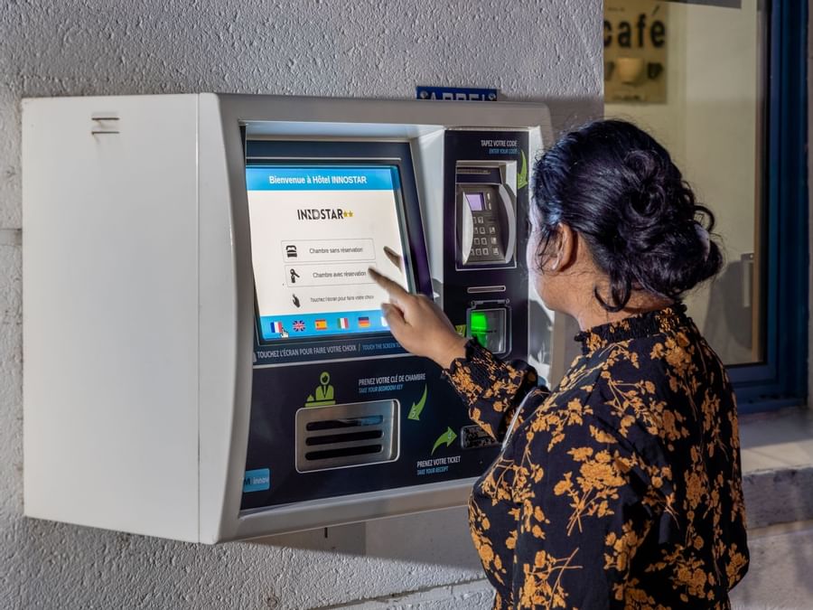 A lady taking money from ATM machine at Hotel Innostar