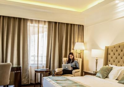 Lady working on the armchair by the bed in Premiere Room at The Indus Valley Leh, Stay in Ladakh