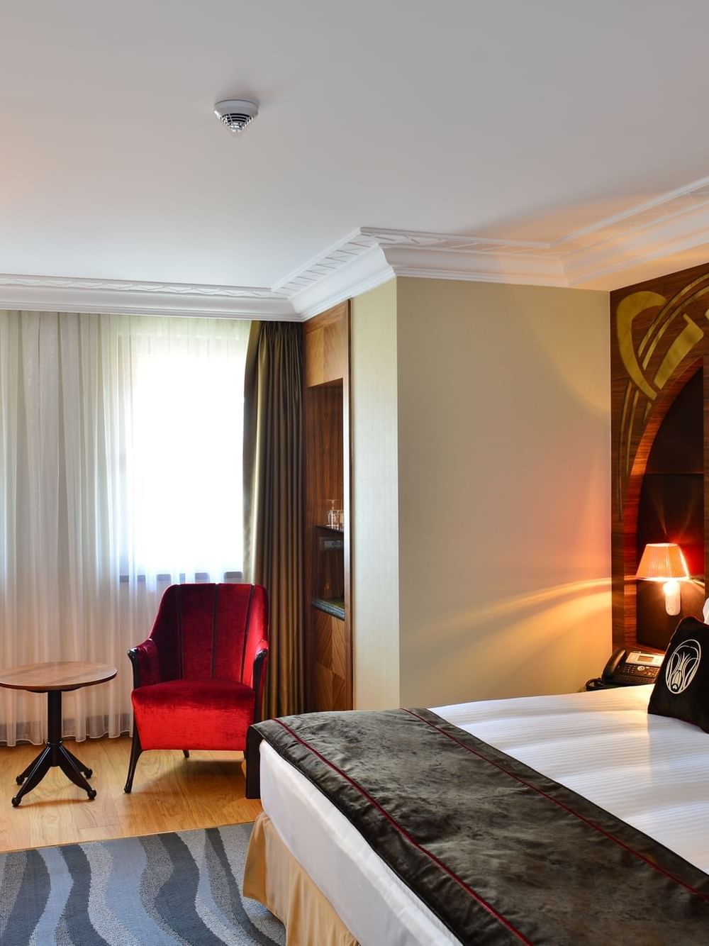 Red velvet chairs by a small table surrounding a bright window in Deluxe Room at Warwick Ankara