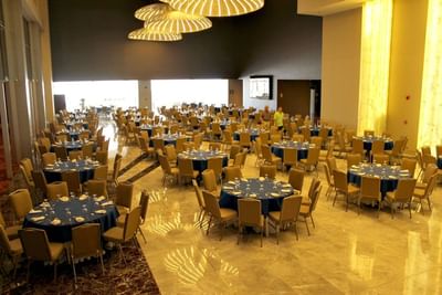 Spacious banquet hall with round tables, blue linens and elegant chandeliers arranged for events at Megapolis Hotel Panama