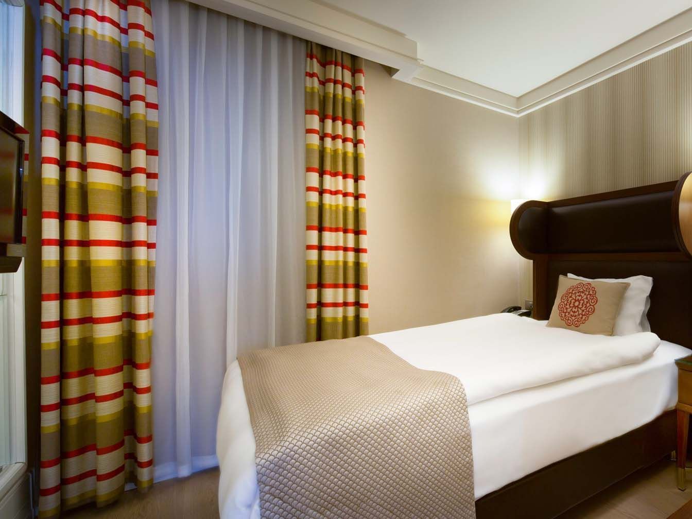 Economic room with a single bed and striped curtains at Titanic Comfort Sisli