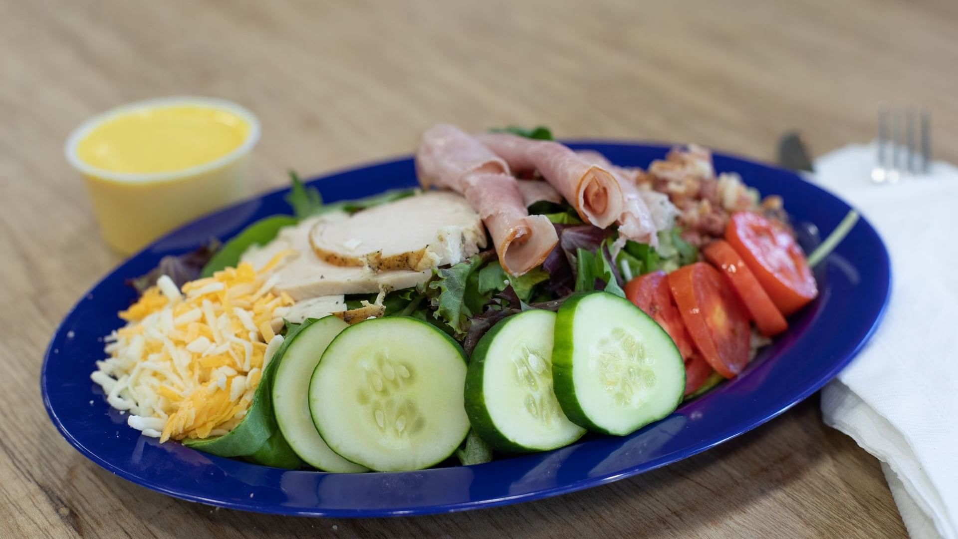 Close-up view of a plate with fresh salad, vegetables, cheese, and dressing at Watersound Inn