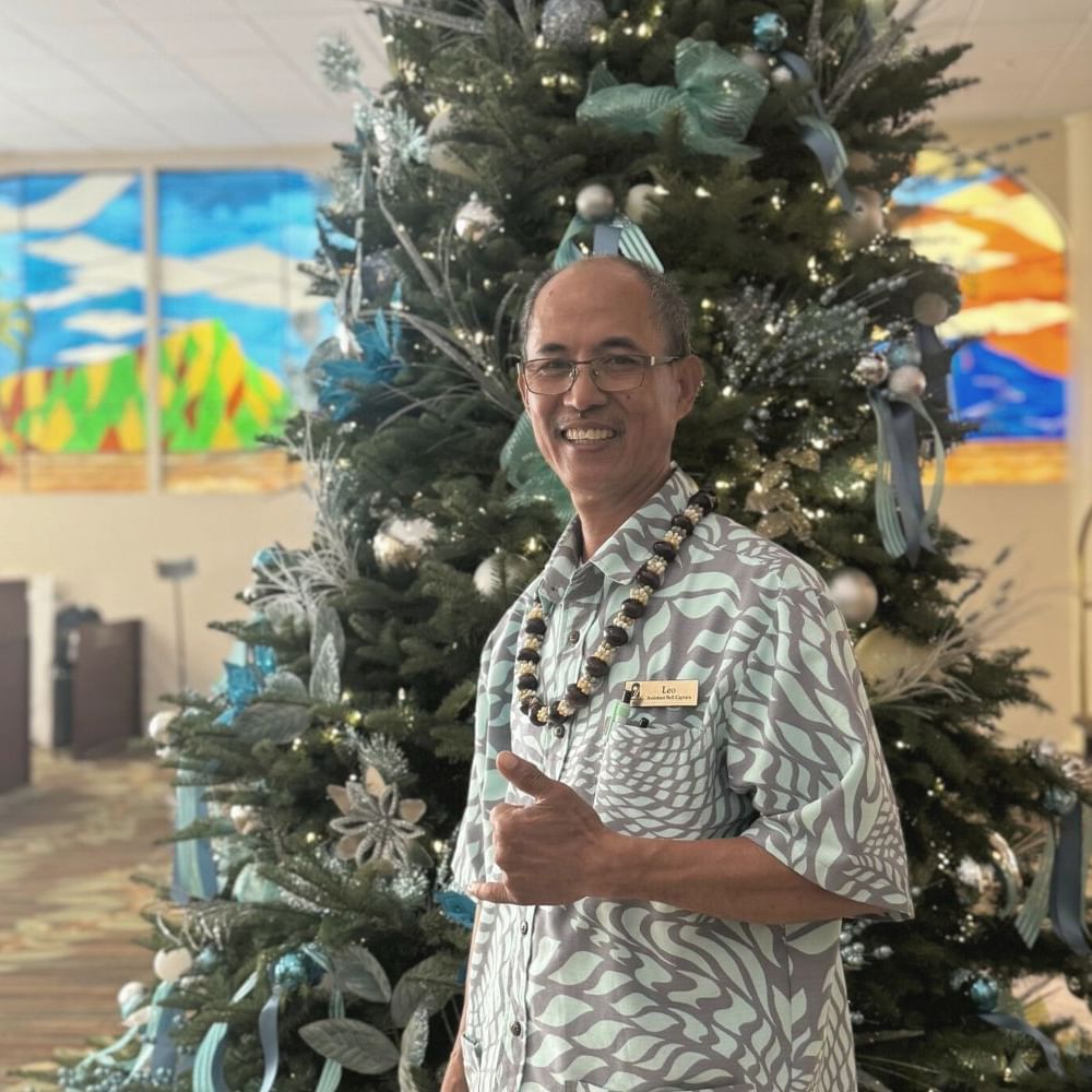 Hotel staff member posing by a decorated Christmas Tree at Waikiki Resort Hotel by Sono