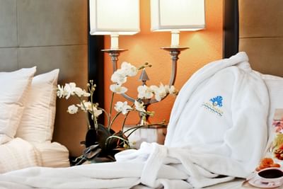 Hotel room with white bathrobe and flowers.