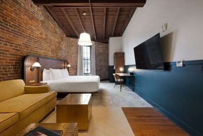 King Junior Suite Accessible with comfy bed, TV, couch and working area at The Delegate Hotel