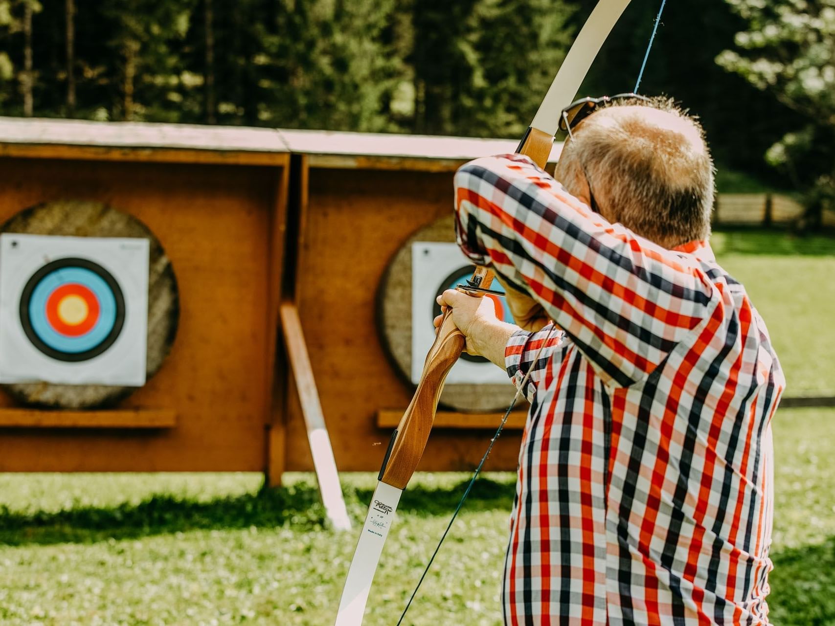 Mann schießt mit Pfeil und Bogen eine auf Zielscheibe im Hotelgarten